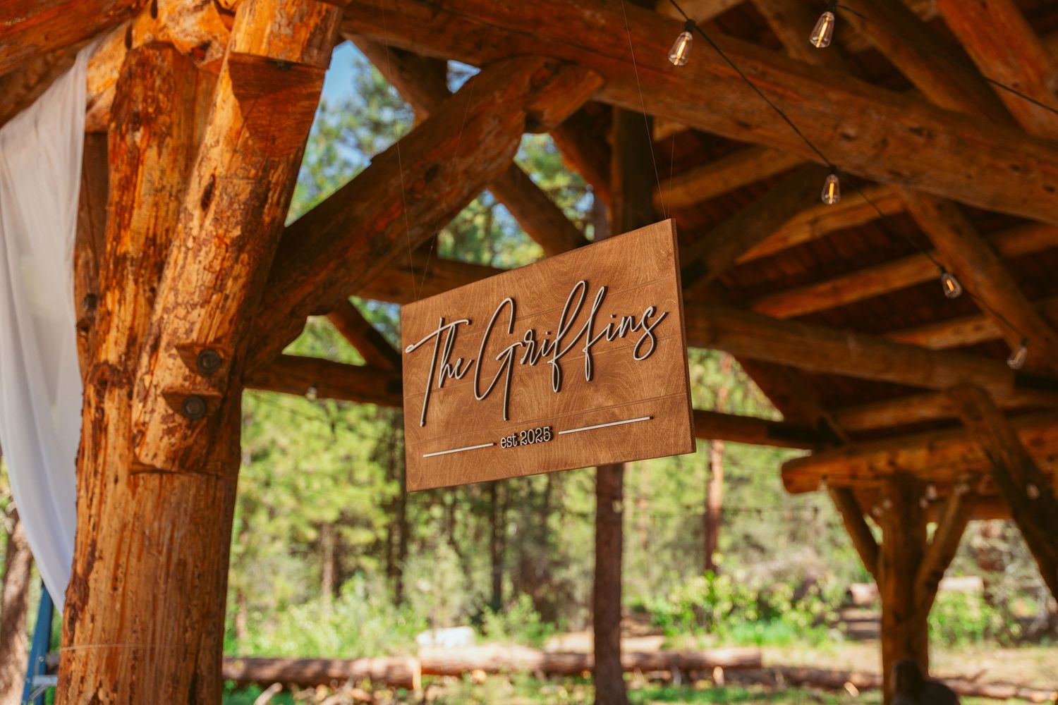Wooden beam ceiling of a rustic outdoor pavilion with decorative signage.