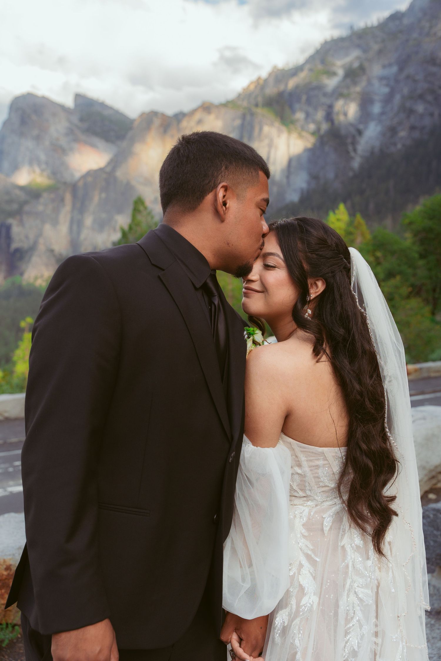 A romantic wedding couple shares intimate kisses against the backdrop of majestic Yosemite Valley cliffs.