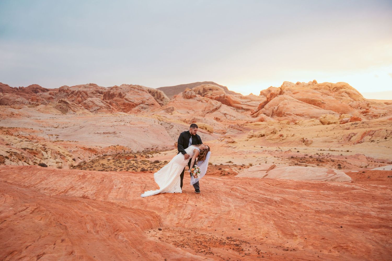 Wedding couple captured in romantic poses across sweeping desert terrain.