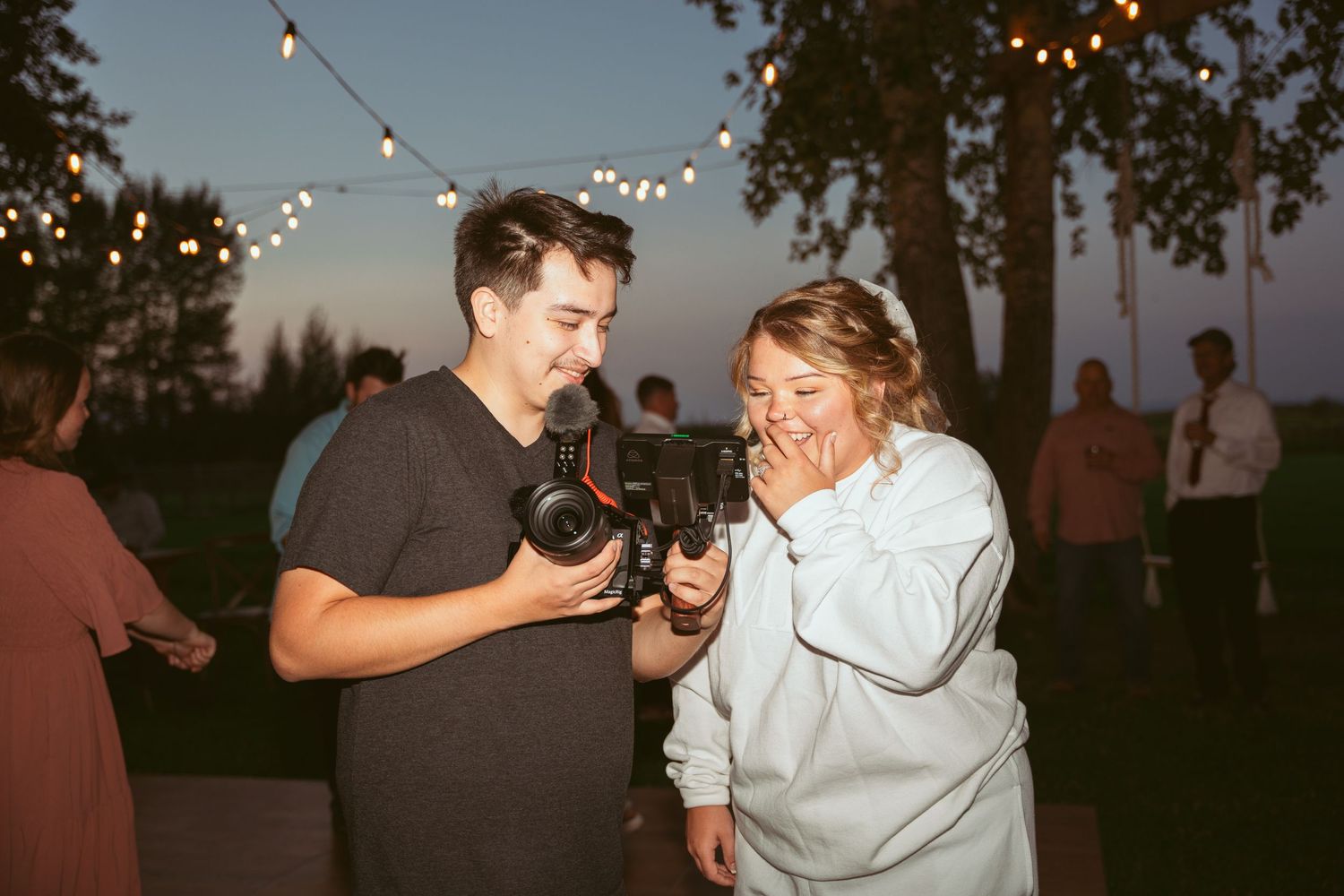 Wedding celebration at dusk with string lights decorating the outdoor venue.