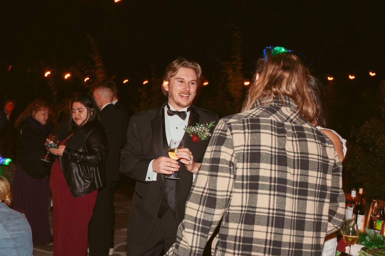Guests dancing and celebrating at an evening wedding reception under warm lighting.