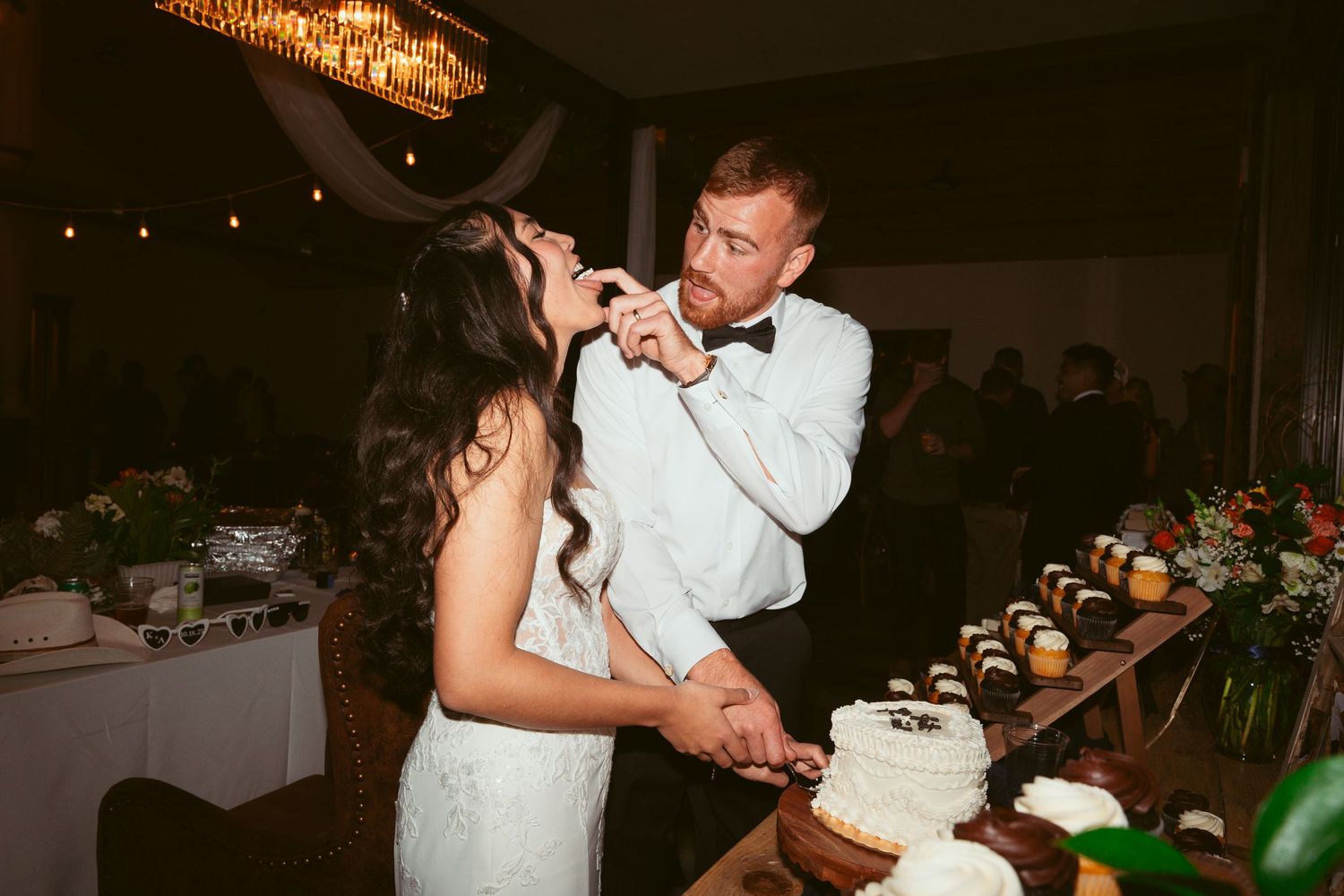 Wedding celebration with dessert table and dancing guests in rustic venue.