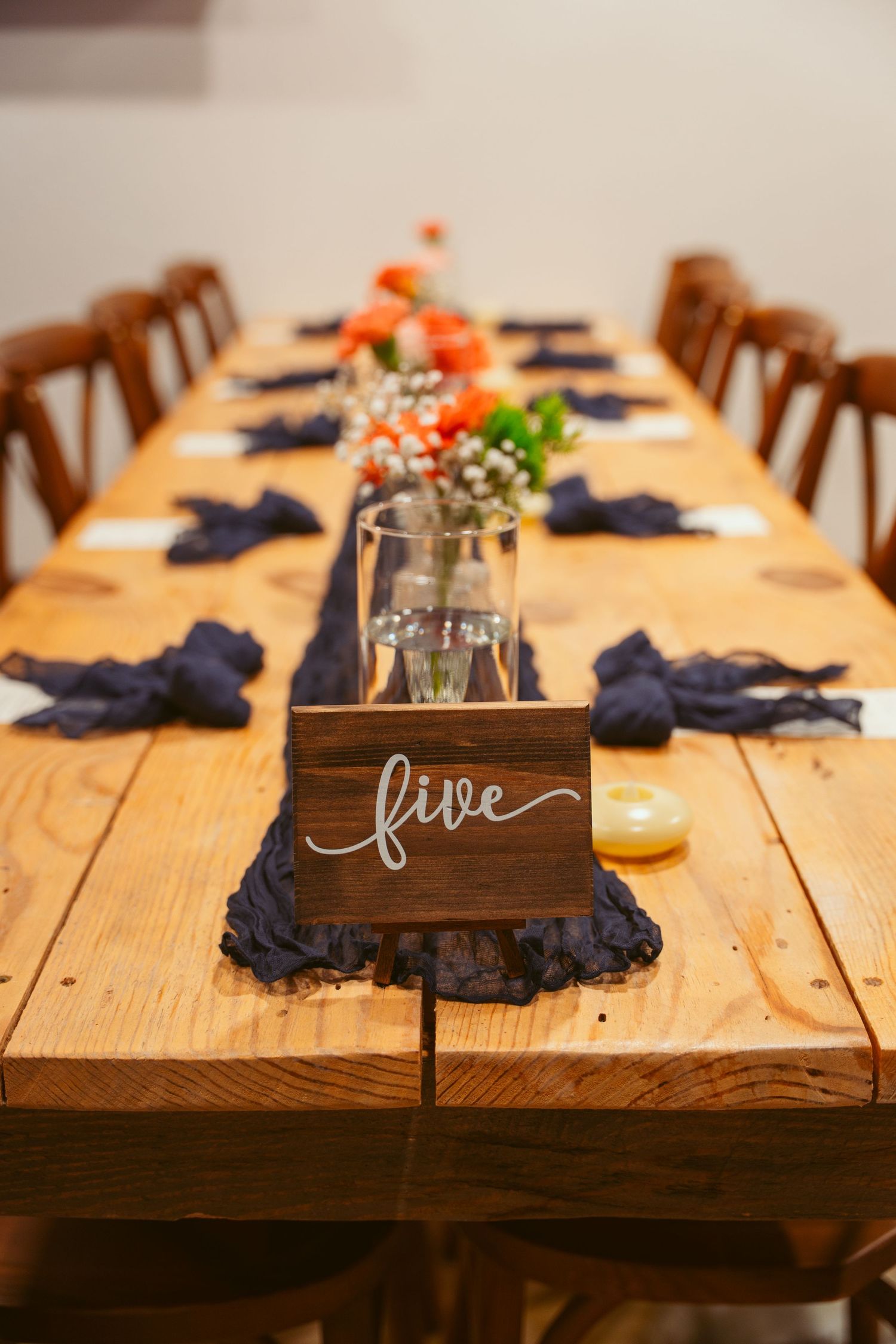 Rustic wooden table decorated with navy blue napkins and small floral centerpieces.