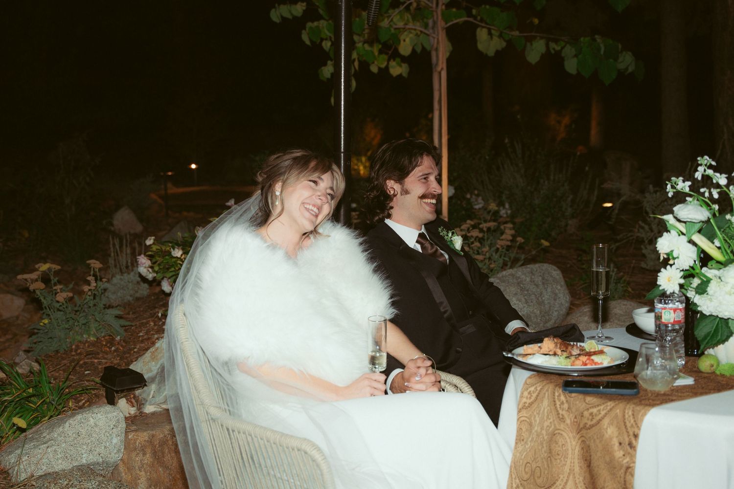 Couple sharing an intimate moment at their outdoor wedding reception with decorative lighting.
