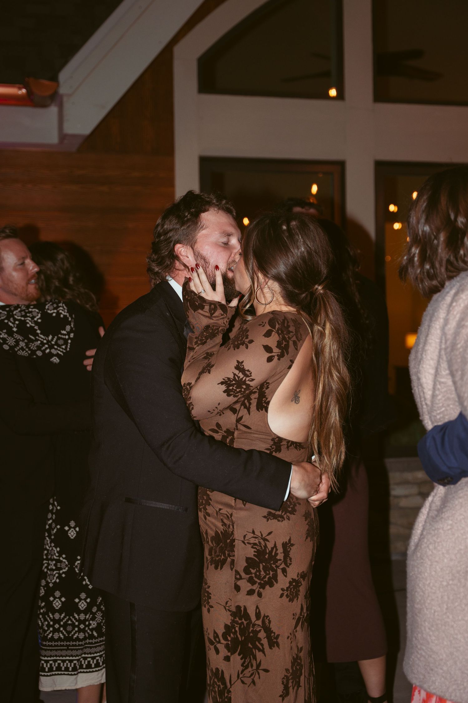 Wedding guests dancing and embracing on a lively dance floor.