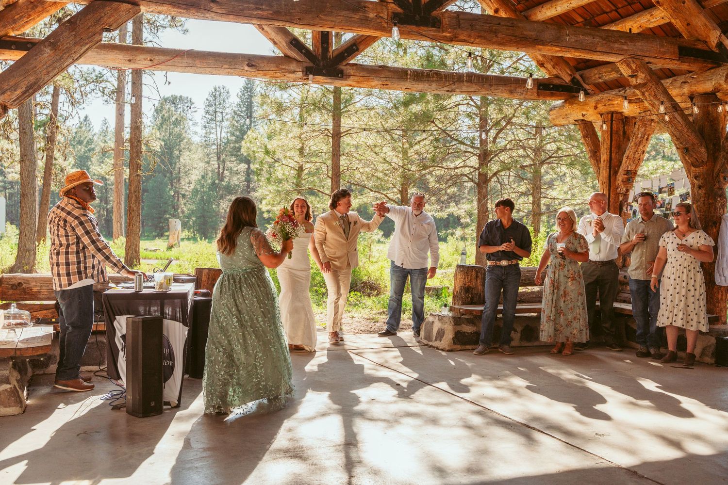 Wedding reception dance party under a wooden pavilion with natural sunlight streaming through.