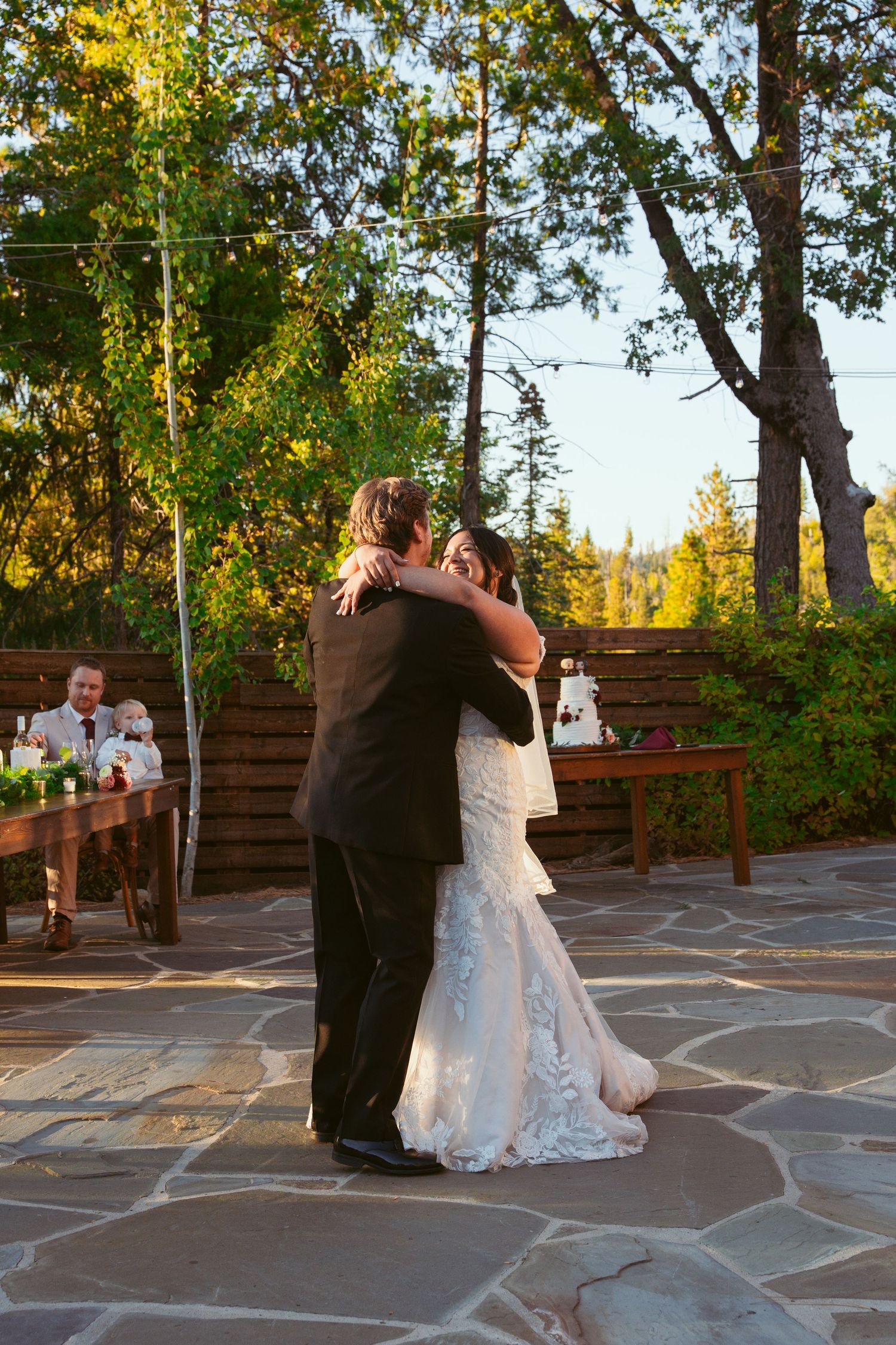 Wedding couple performs romantic dance moves on a rustic stone patio at sunset.