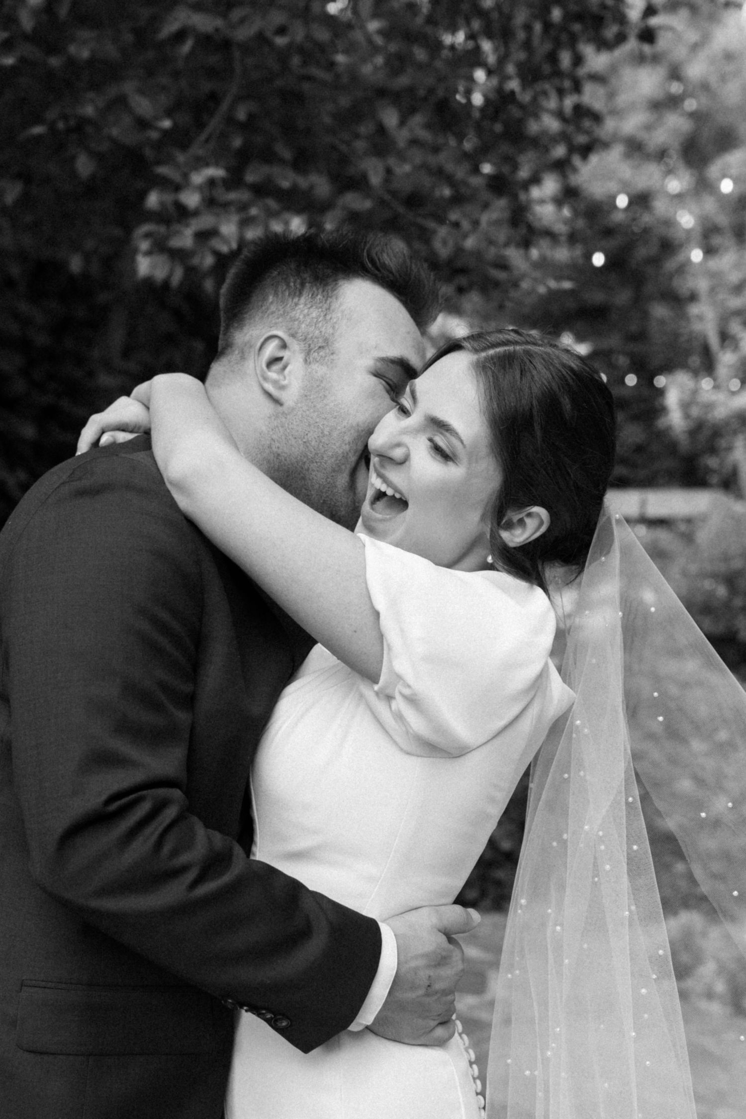 Black and white wedding portraits showing tender embraces between newlyweds outdoors.