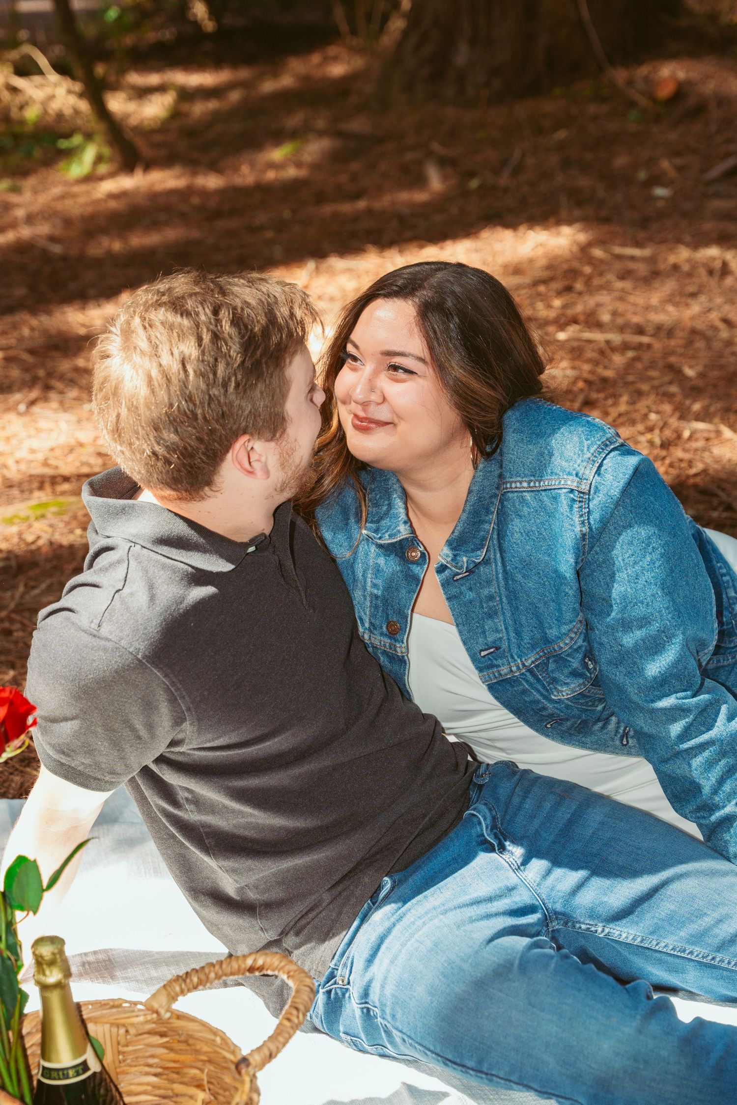 A romantic picnic scene with wine and roses set in a peaceful redwood forest.