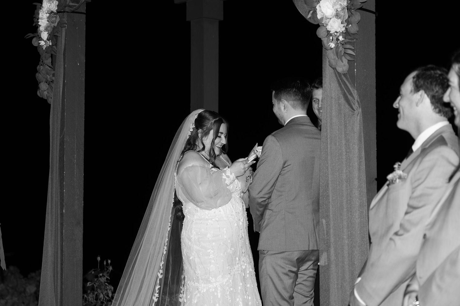 Wedding ceremony moment captured in black and white under an elegantly decorated pavilion.