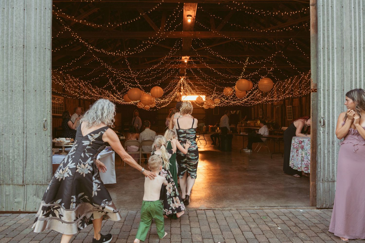 Wedding celebration features synchronized dancing on brick patio with ambient lighting.