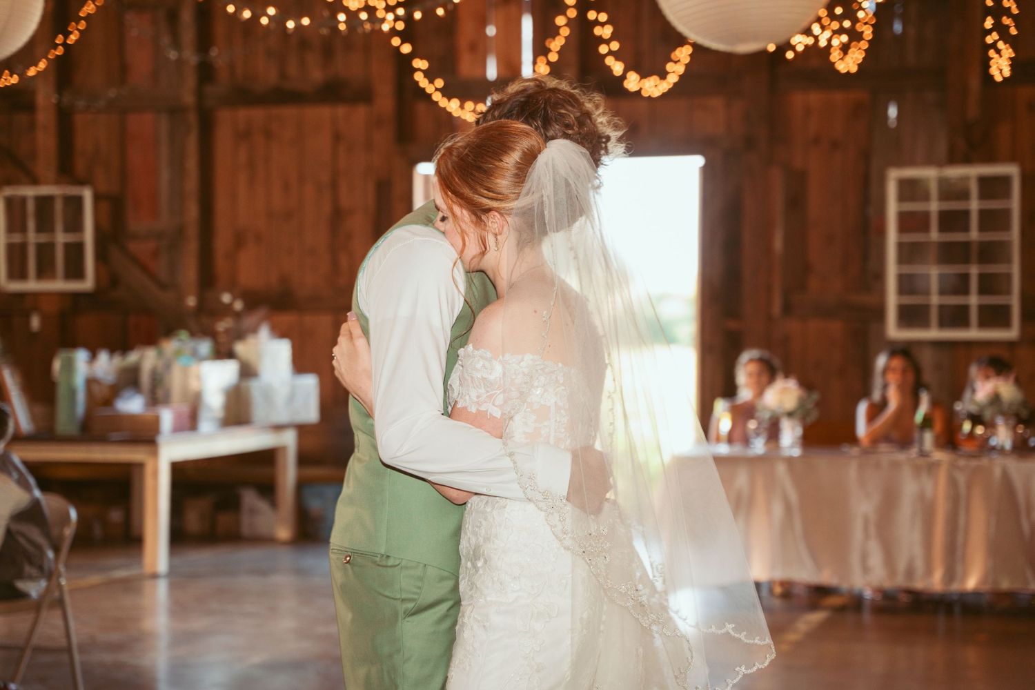 Rustic barn wedding reception with twinkling lights and white paper lanterns creating a romantic atmosphere.