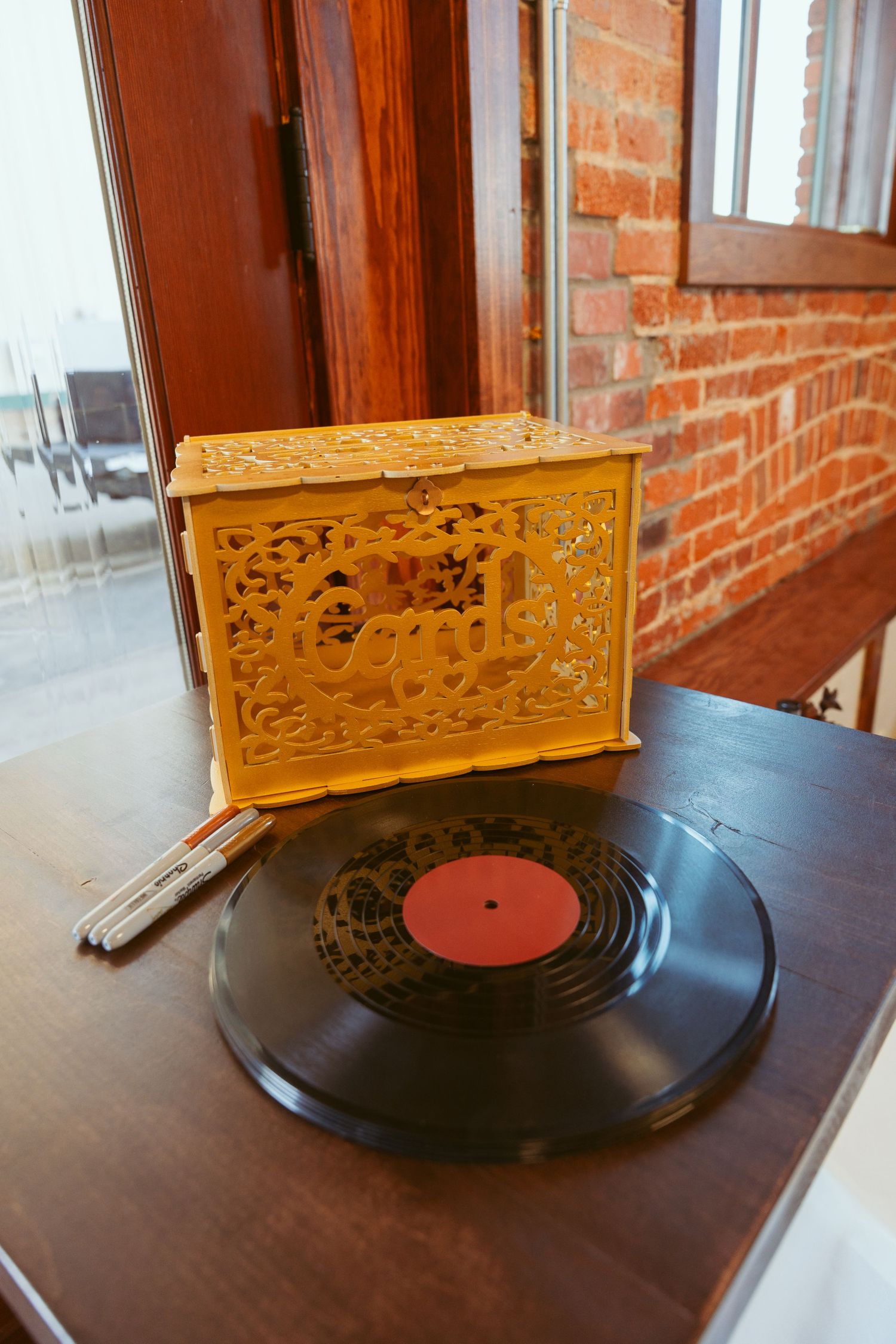 Vintage vinyl record with decorative golden box on wooden table against brick wall.