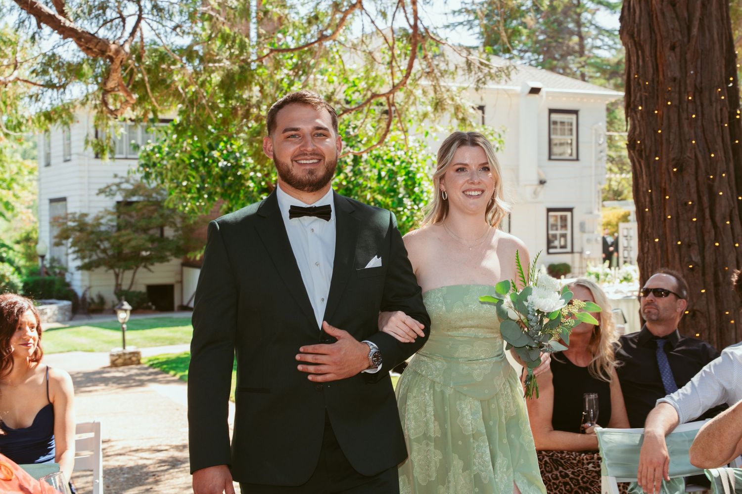 A joyful wedding processional moment outdoors with a historic building in the background.
