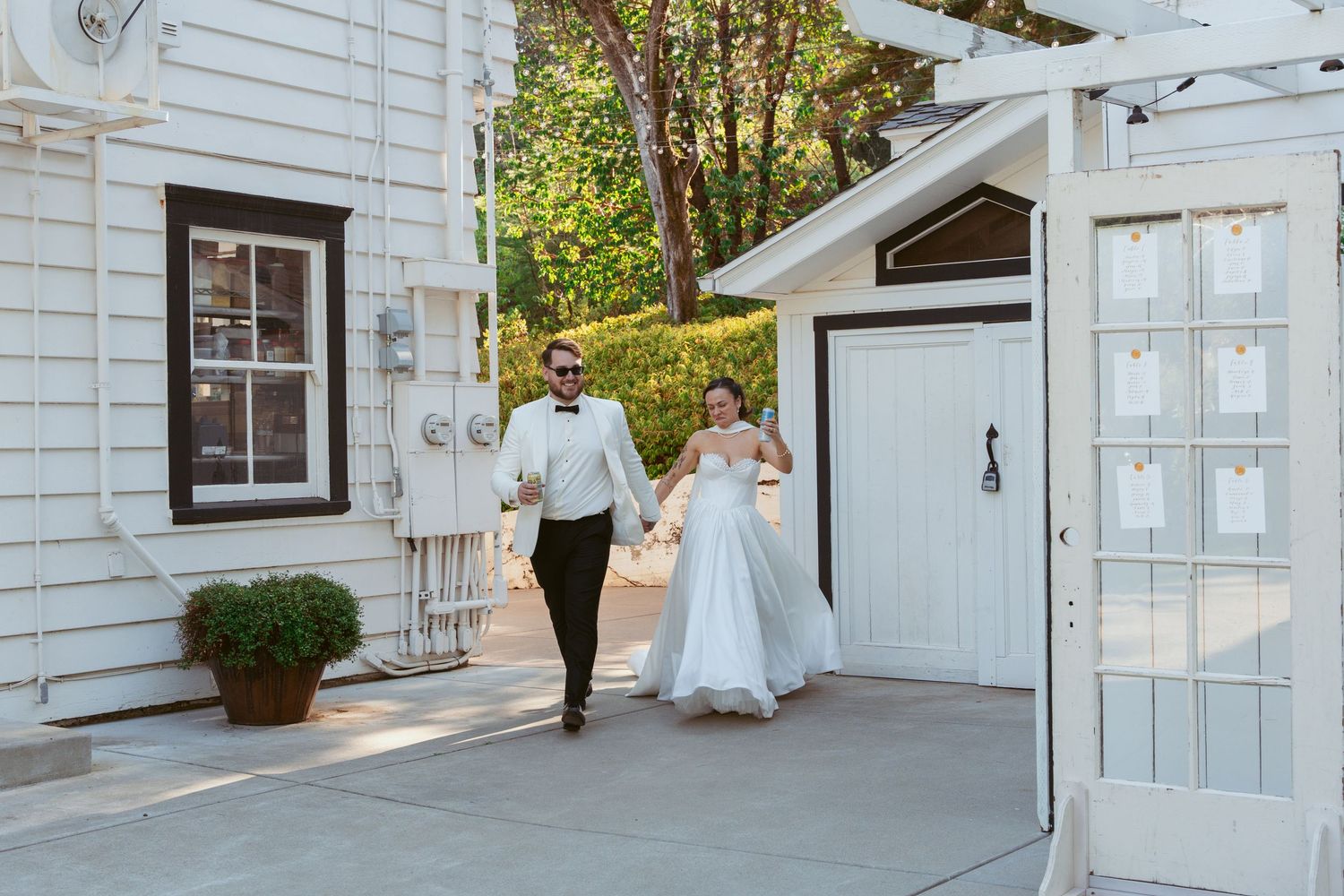 Elegant outdoor wedding reception setup with white building and greenery in background.
