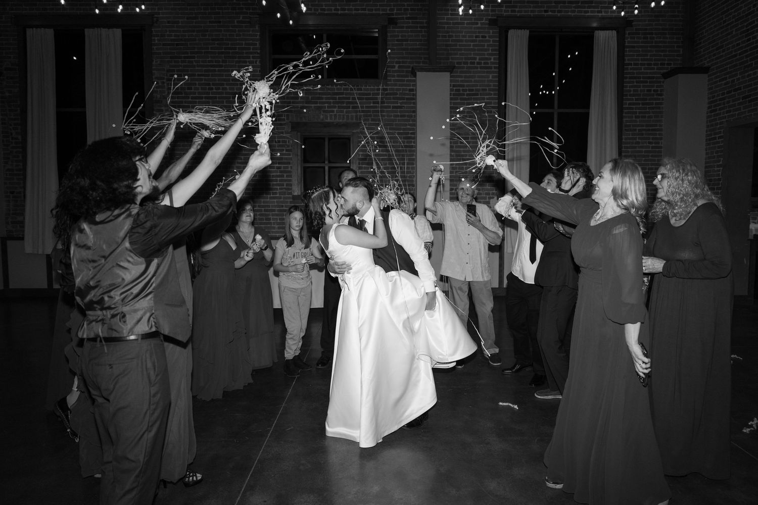 Black and white capture of wedding celebration with guests throwing streamers in the air.