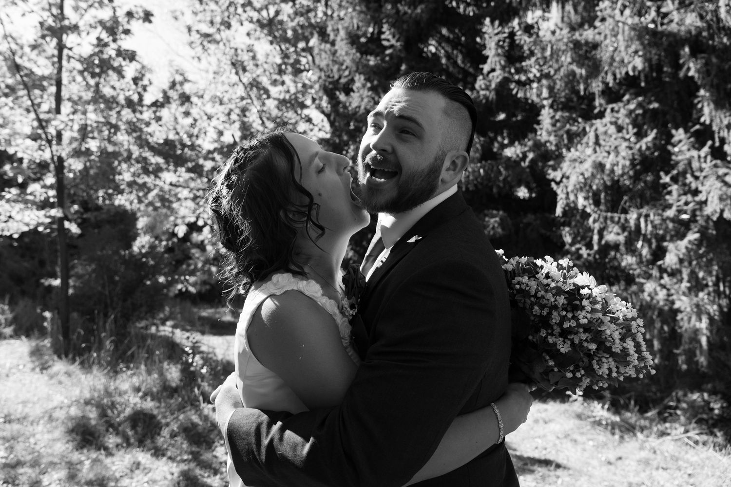 A romantic black and white wedding photo of a couple sharing an intimate moment outdoors.