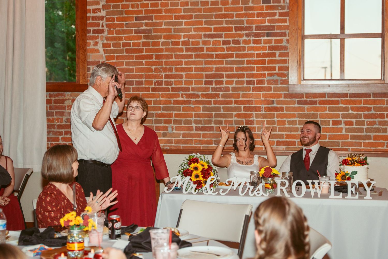 Elegant wedding reception space with exposed brick walls and custom name signage.