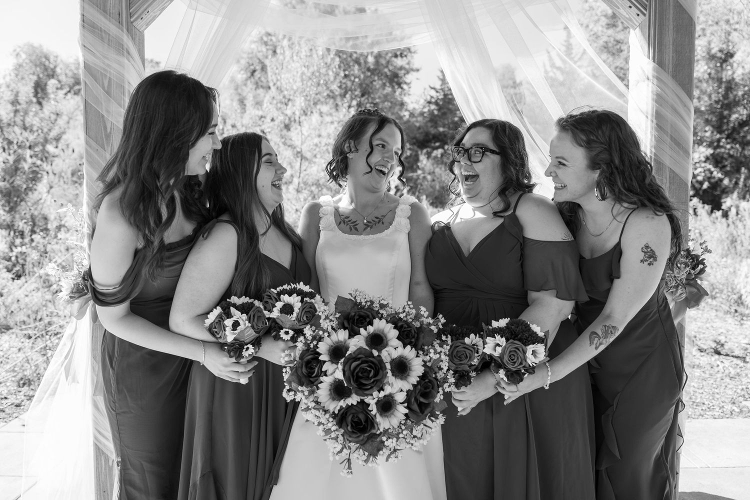 Black and white candid photo of wedding party sharing joyful moments.