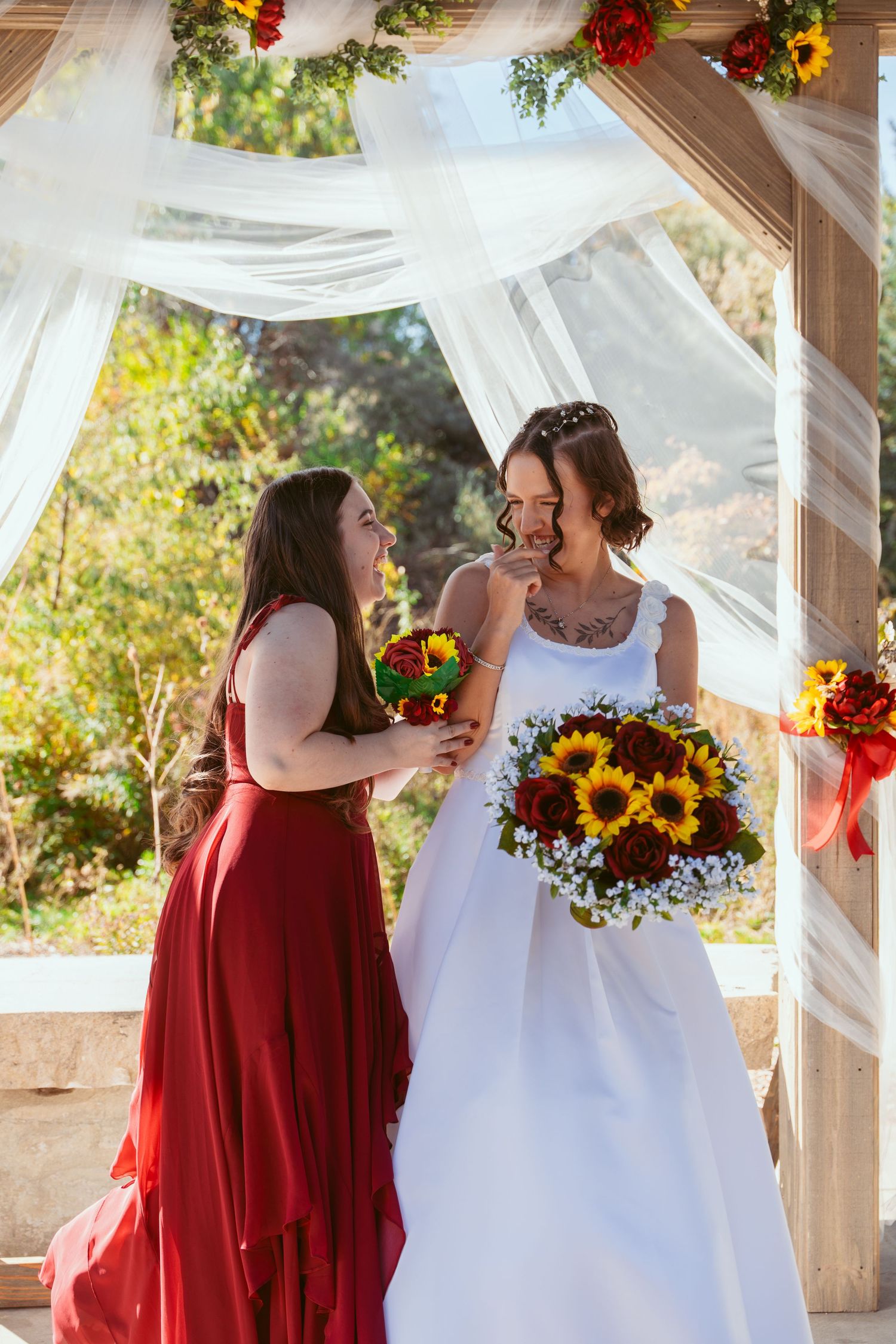 Wedding celebration under a decorated pergola with white fabric and red accents.