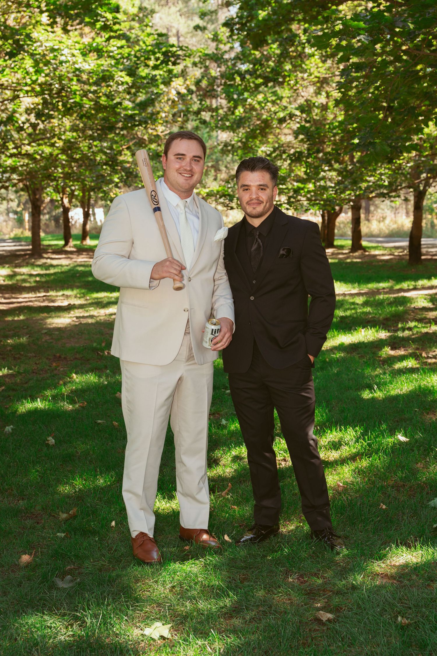 Groomsmen in white suits and black tuxedos gather for outdoor photos.