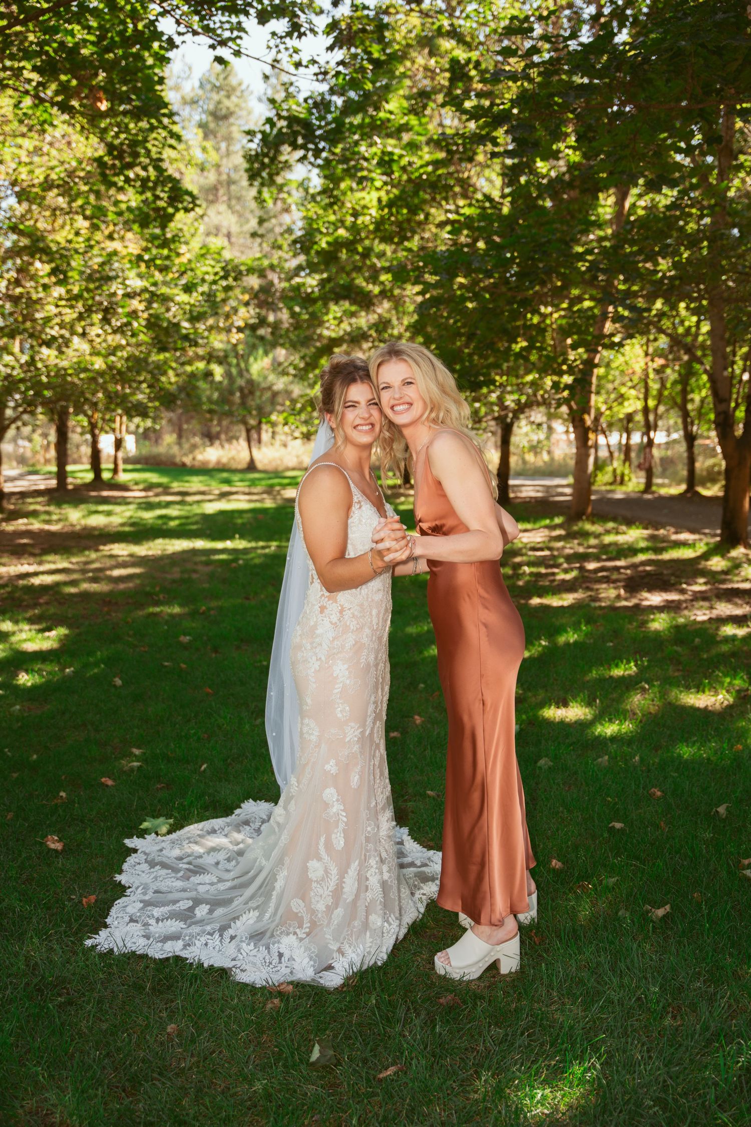 Wedding party members sharing candid moments in a sunny outdoor garden.