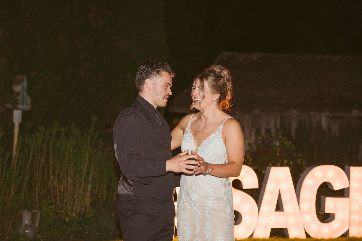 Illuminated outdoor wedding reception venue with dance floor and glowing signage.