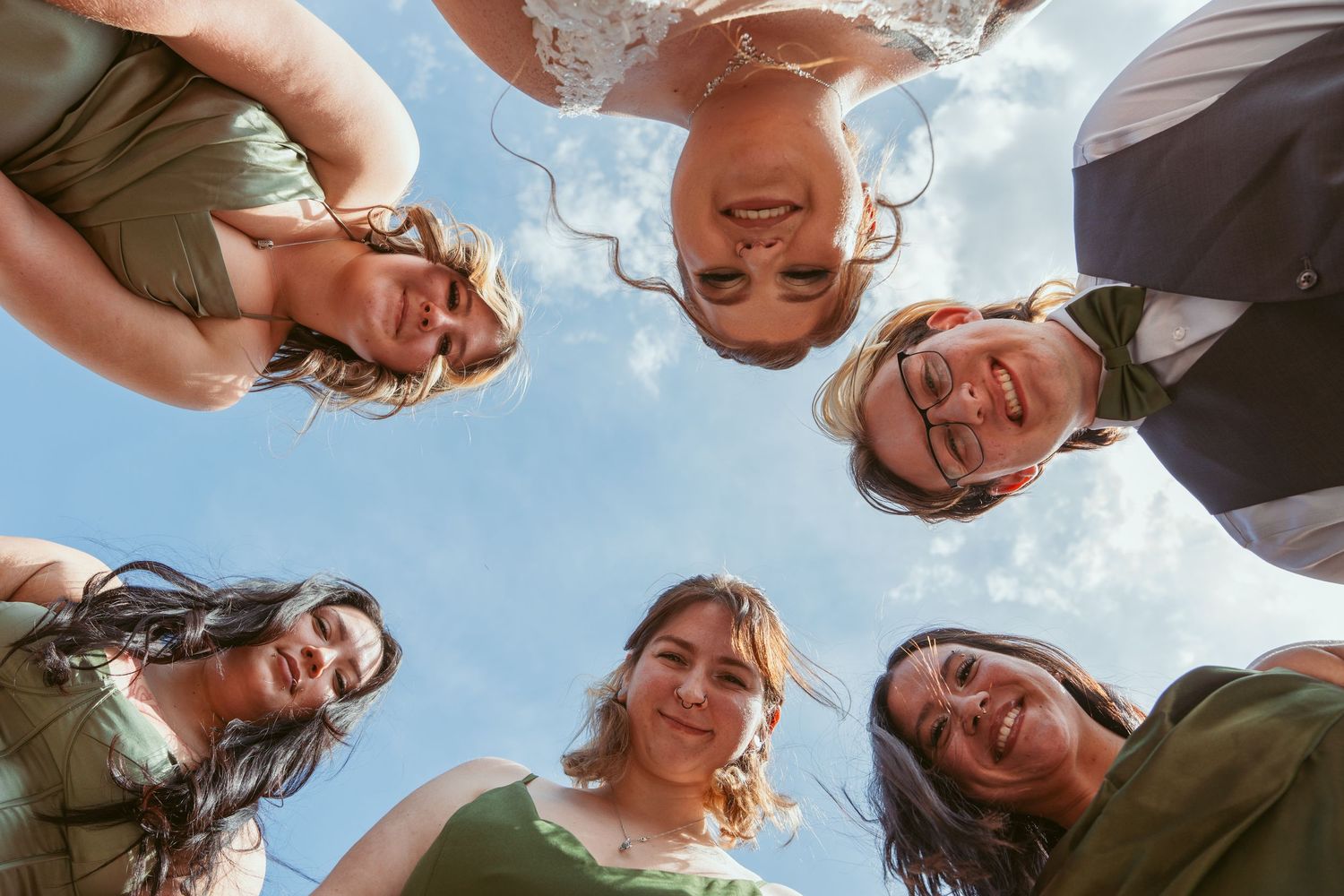 Group photo taken from below against blue sky with people looking down at camera.