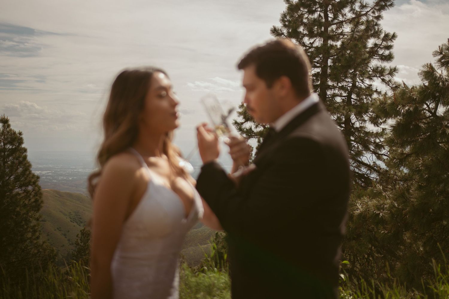 Two people share an intimate dance moment on a mountain trail during a sunny afternoon.