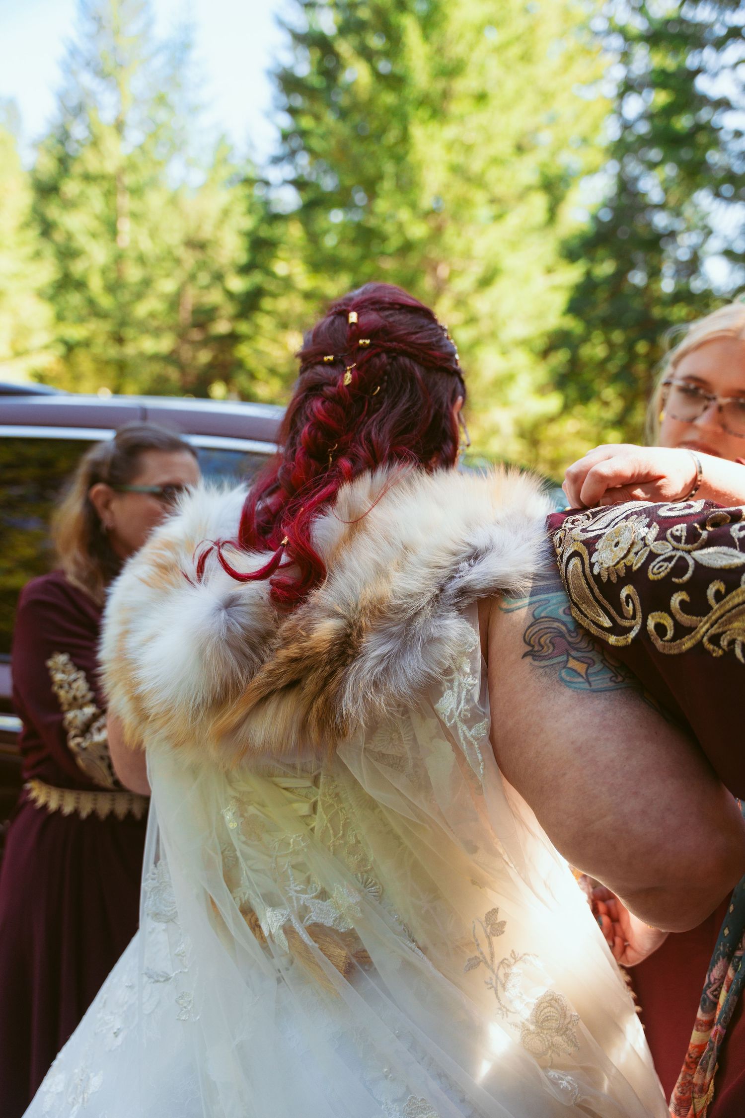 Close-up details of a white wedding dress with fur trim and burgundy accents.