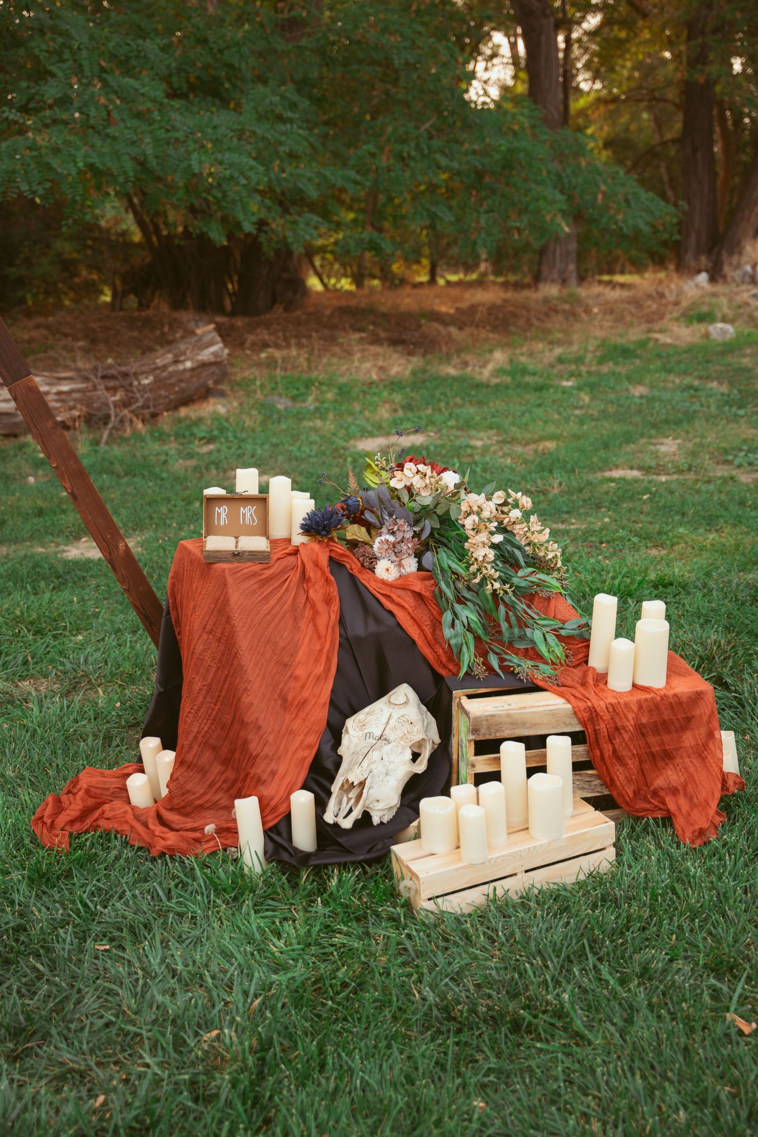 Outdoor scene with wooden blocks, candles, and red fabric arranged on green grass.