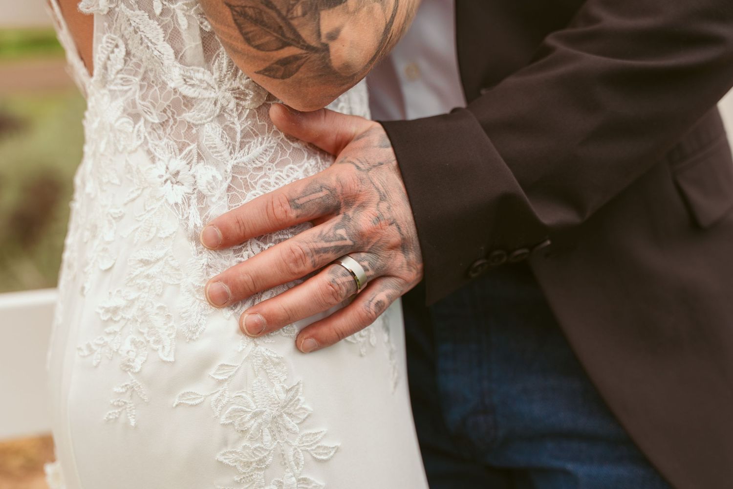 Close-up detail of lace wedding dress with hands visible.