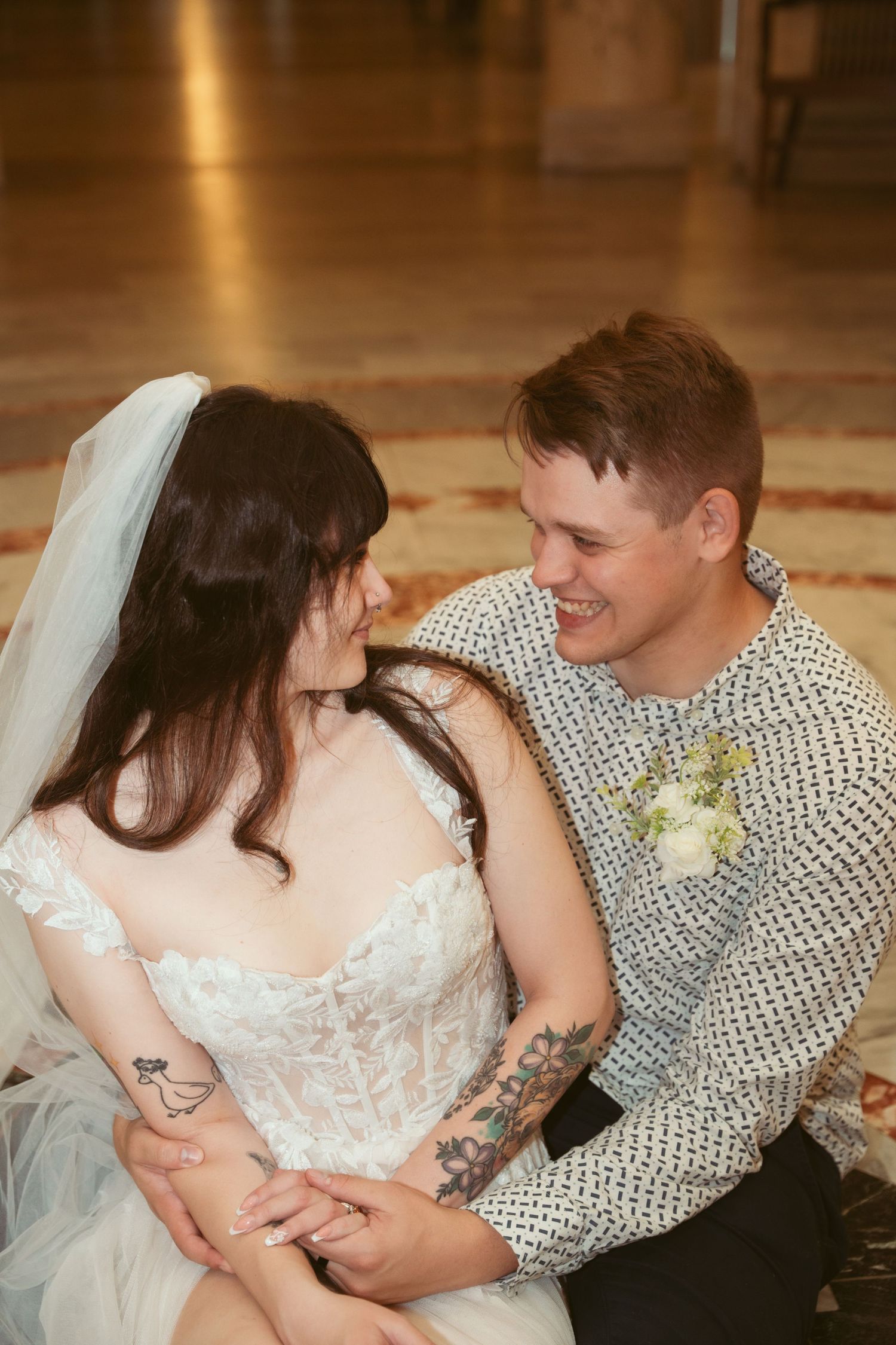 Bride and groom share intimate moments while sitting together in a grand ballroom.