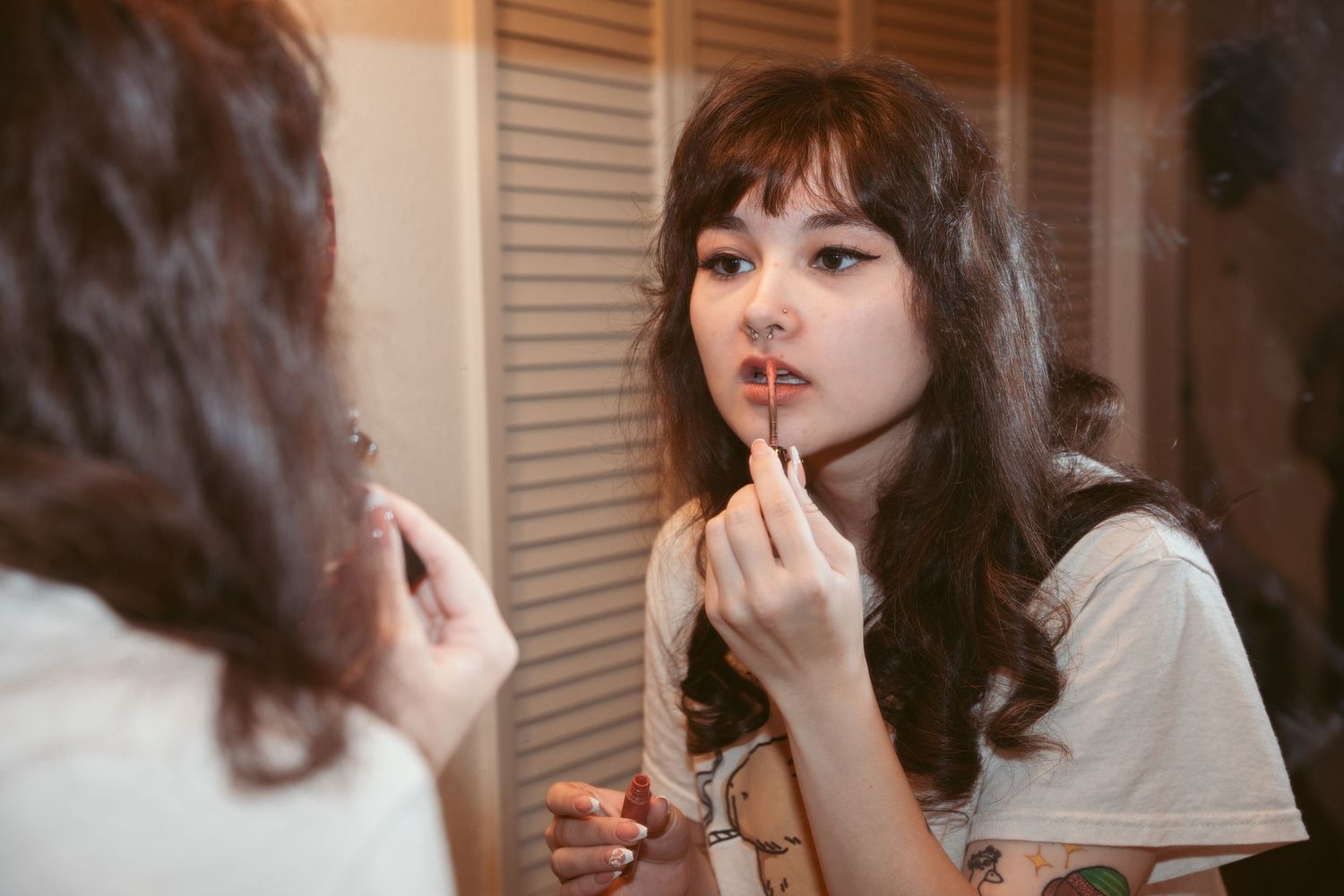 A person applies makeup in front of a mirror during wedding preparations.