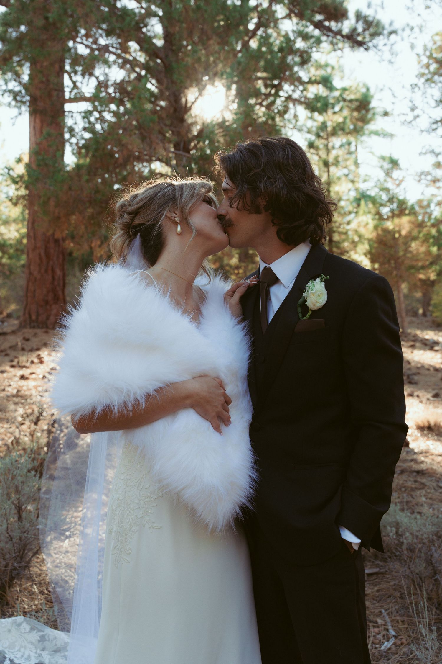 An intimate wedding moment captured in a serene forest setting with natural lighting.
