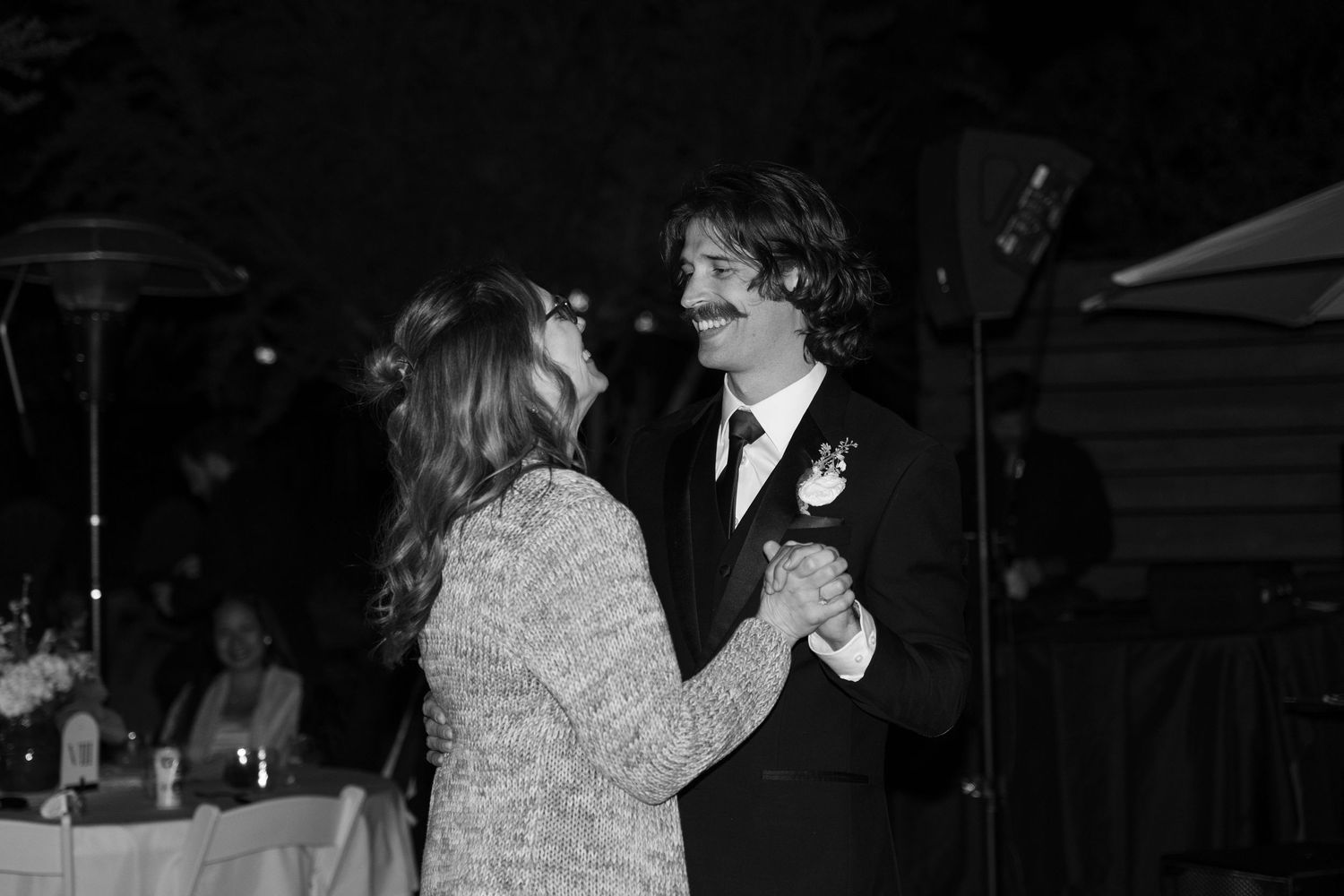 Black and white photo of a couple dancing together at an outdoor evening celebration.