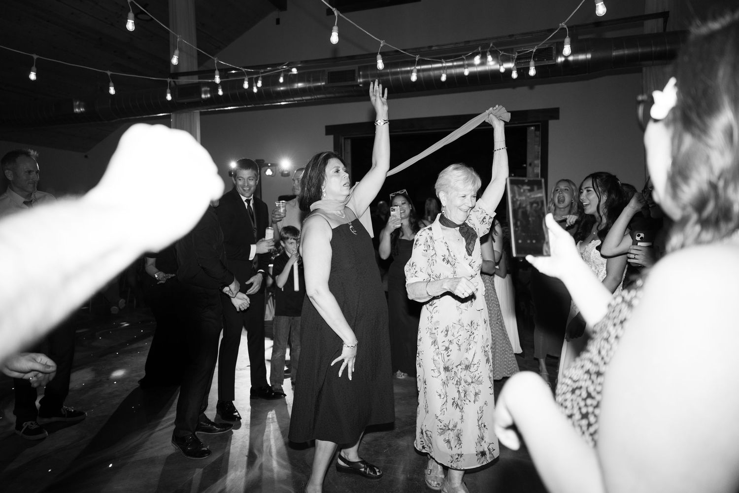 Festive dance floor filled with celebrating guests under ambient string lighting.
