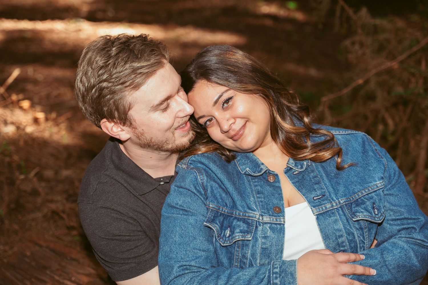 Tender moment captured between couple in natural forest lighting.