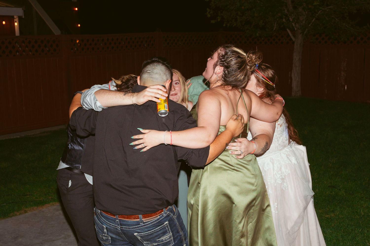 A group hug captured during an emotional moment at an outdoor wedding reception.