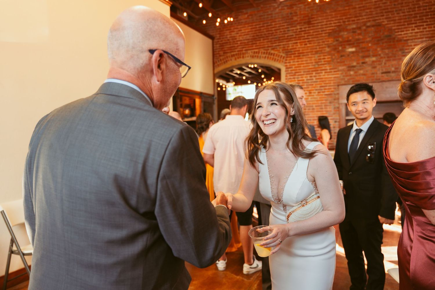 Wedding celebration candid moments captured during dancing at an indoor brick venue.