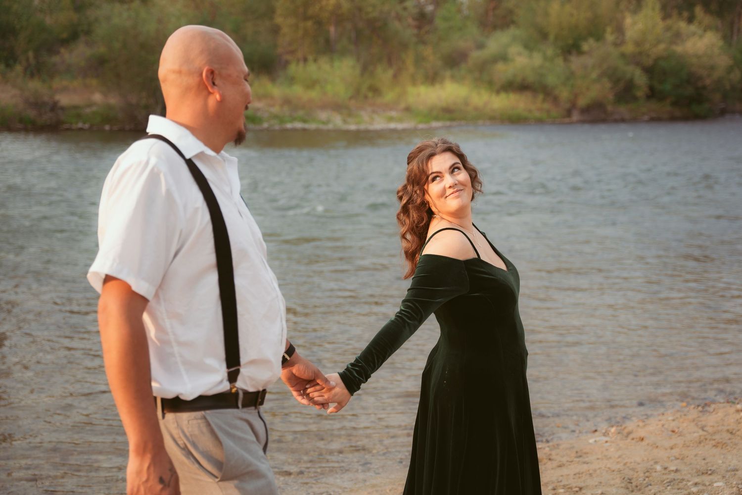 A couple shares a tender moment by the waterfront during golden hour.