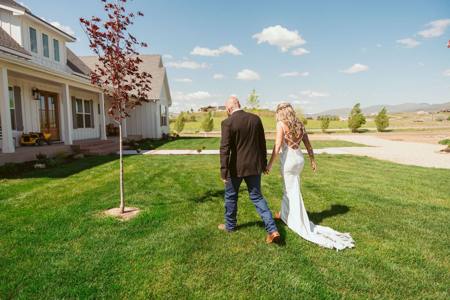 Scenic outdoor wedding venue with white chairs set up on a manicured lawn near a building.