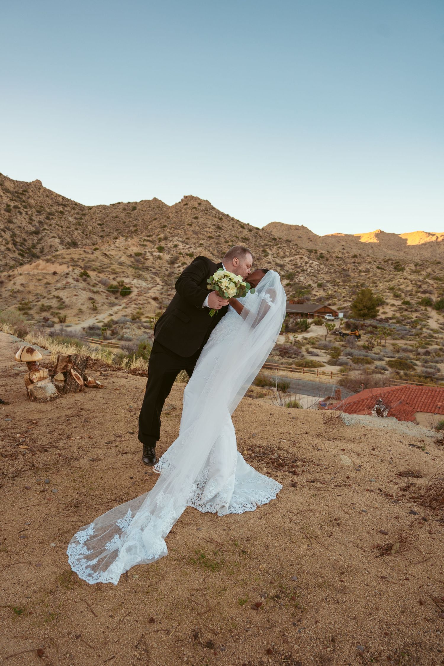 Wedding couple poses for photos against scenic desert mountains during golden hour.