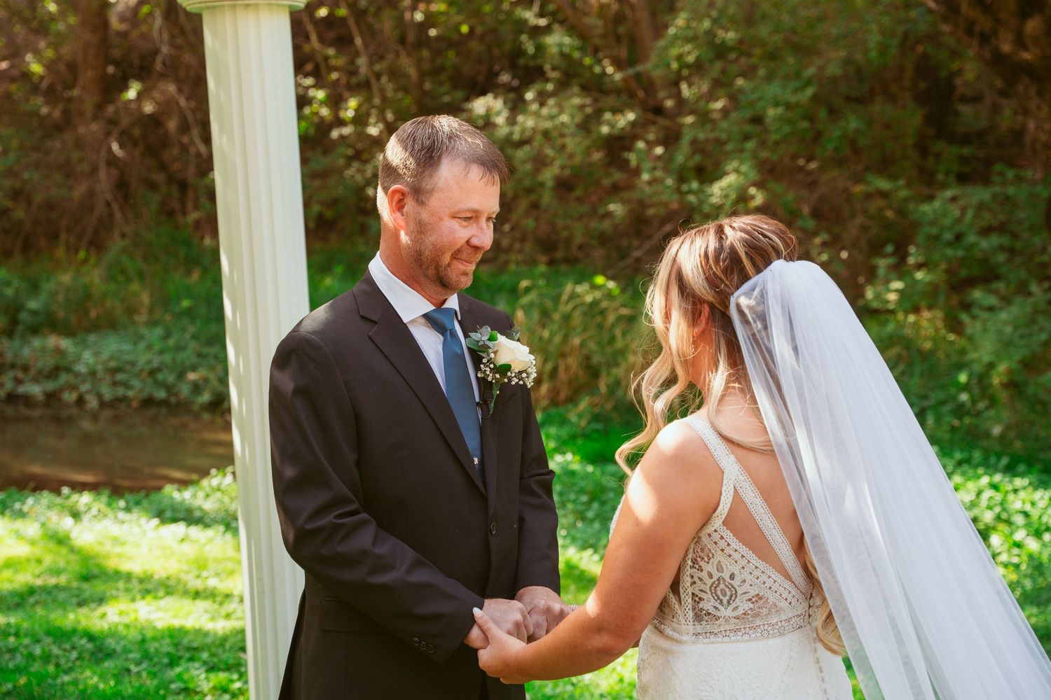 A romantic wedding moment captured under a white gazebo surrounded by lush greenery.