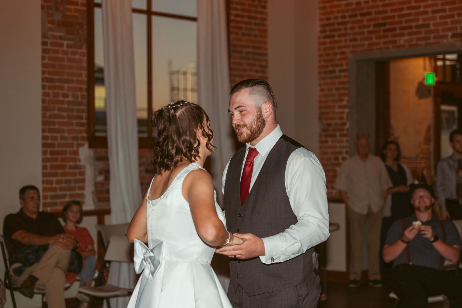 Couple performs elegant dance moves during their wedding reception in an industrial chic space.
