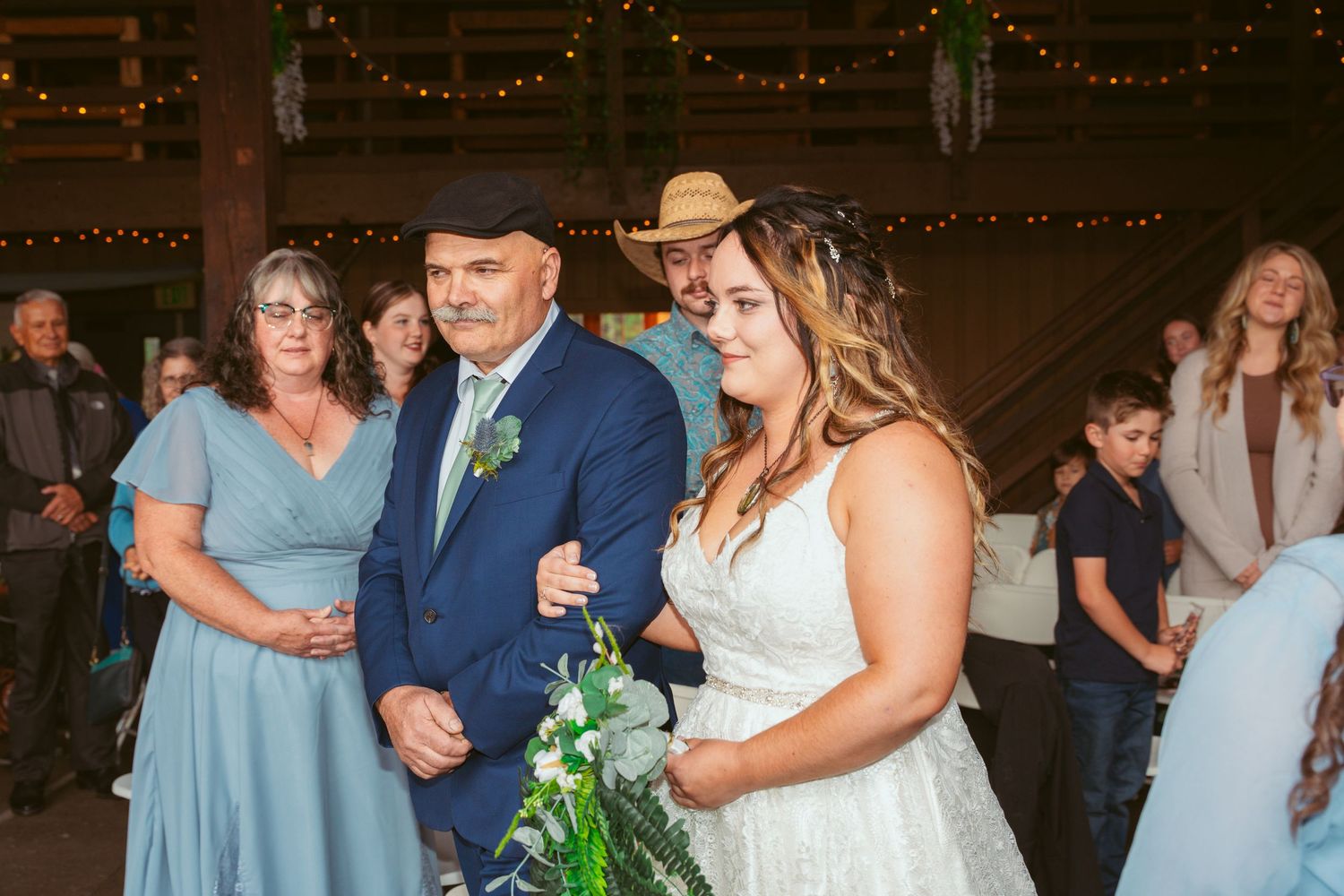 Wedding party celebrating in a barn decorated with twinkle lights and rustic wooden beams.