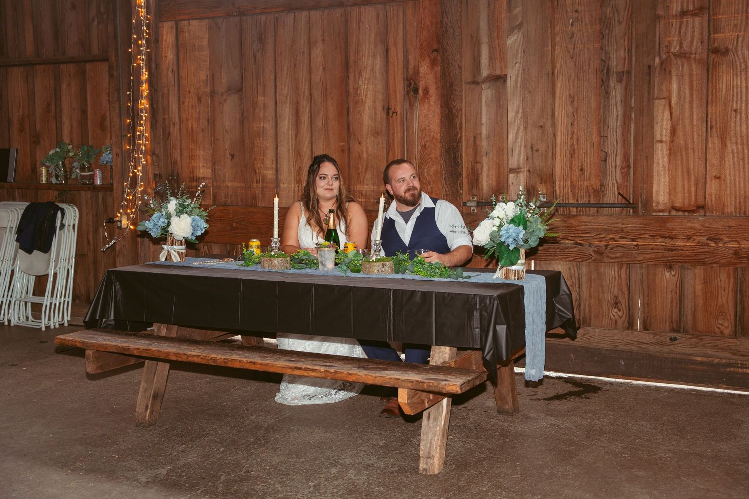 Rustic barn wedding reception with elegant table settings and romantic lighting.