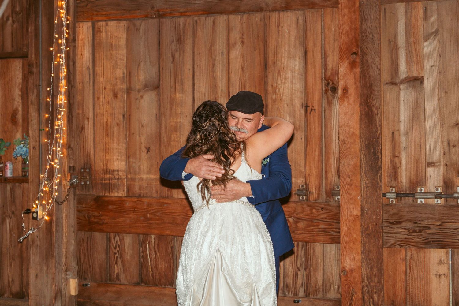 Couples dancing together in a rustic barn venue with warm lighting.