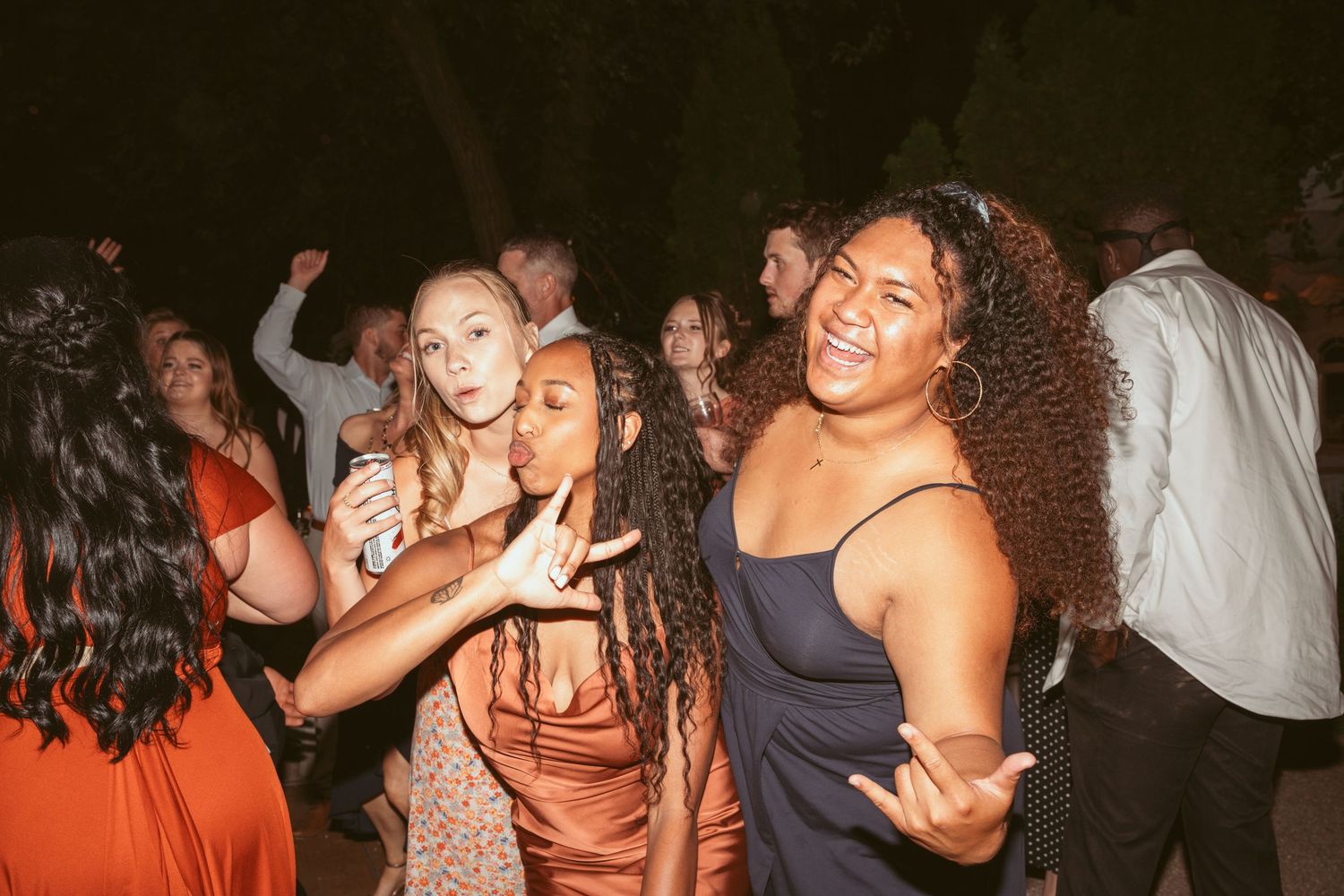 Guests dancing and celebrating at a lively wedding reception party with warm lighting.