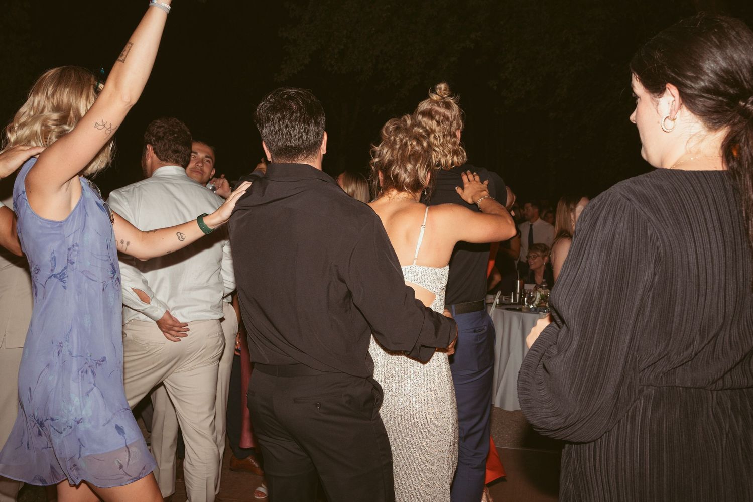 Wedding guests dancing together at a nighttime reception celebration.